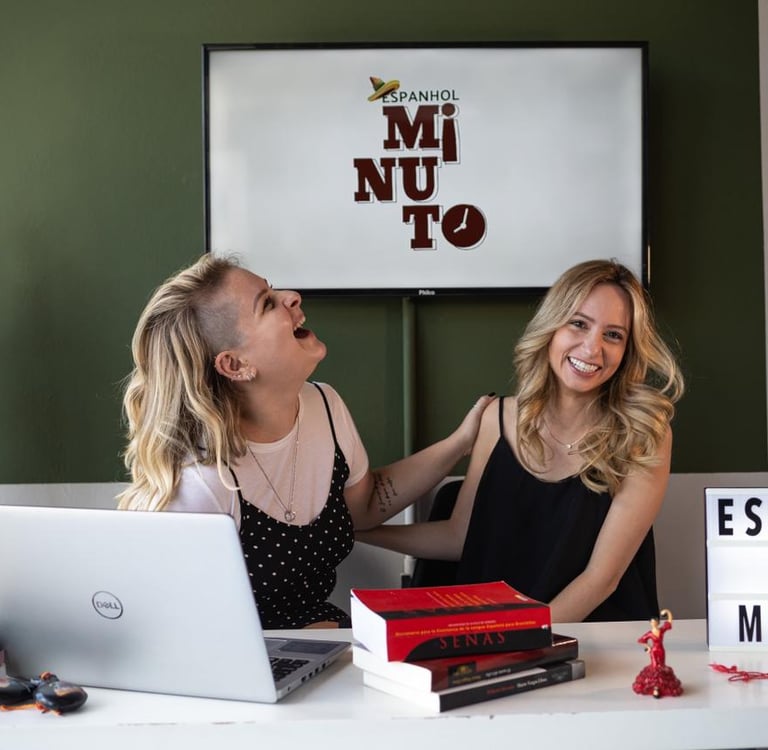 two women sitting at a desk with a laptop