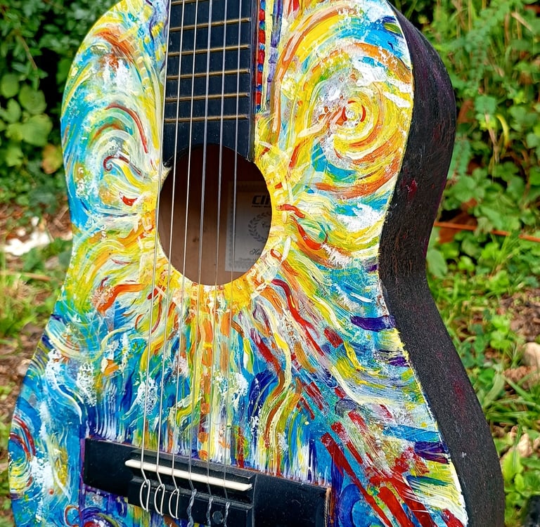 peinture sur guitare aux couleurs vives, avec un soleil autour de la rosace et des formes abstraites