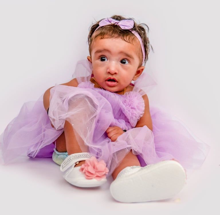 a baby girl in a purple dress and white shoes