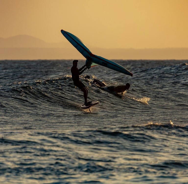 Wingfoil surfing on a wave during sunset