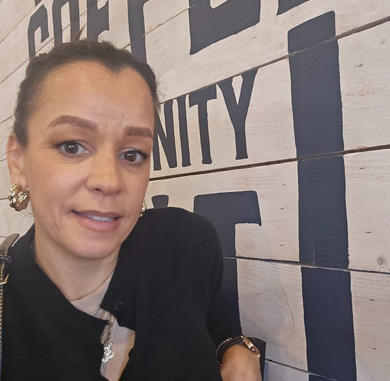 Close-up lifestyle selfie inside a coffee shop with bold wall typography in the background