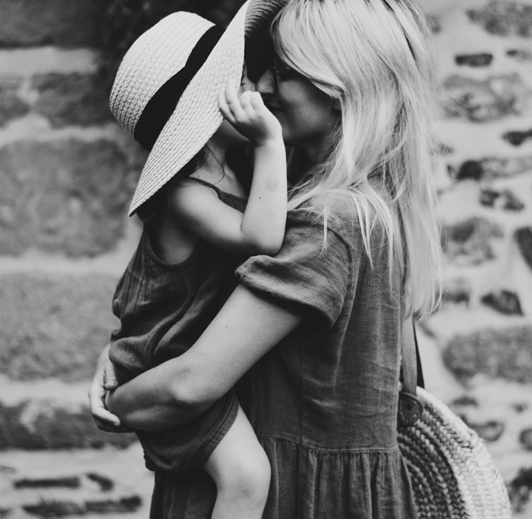 a woman in a hat and sunglasses is holding a baby