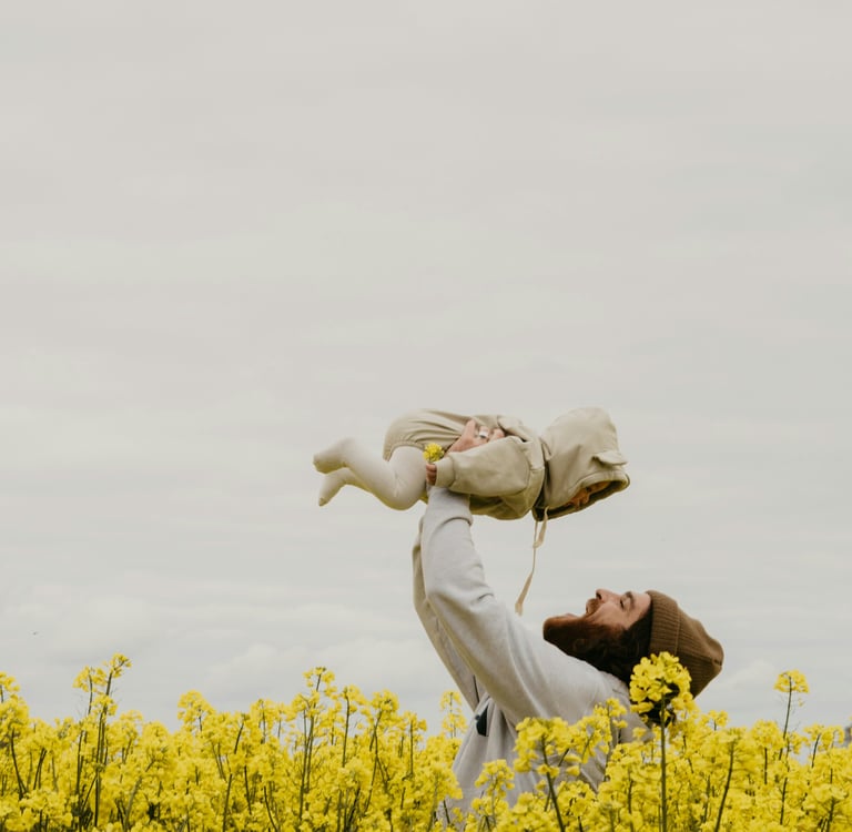 a man holding a baby in a field