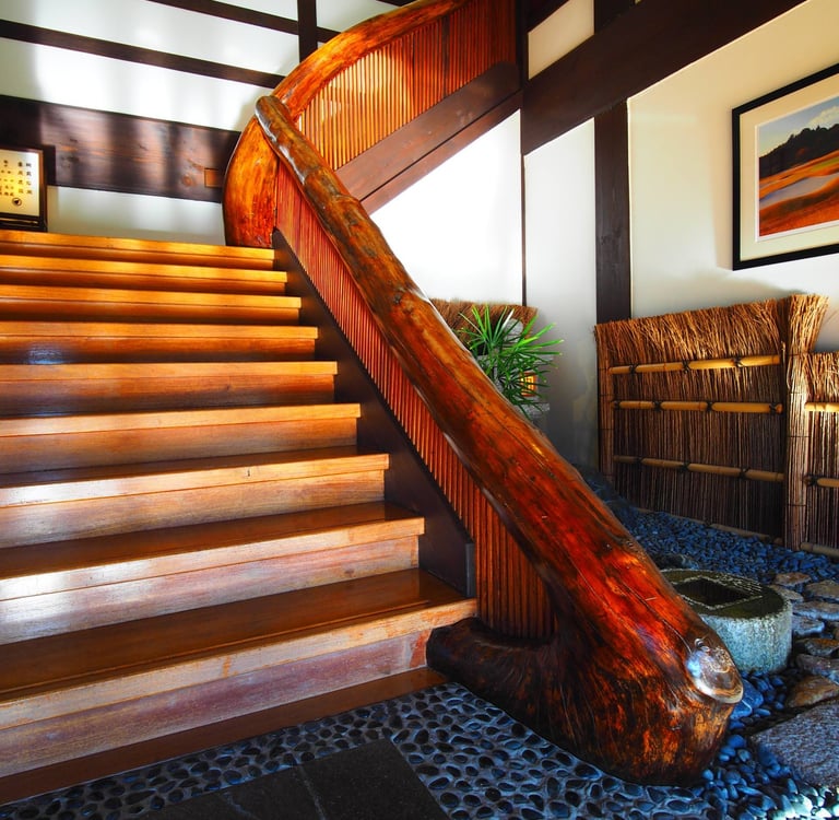 Traditional Japanese interior featuring a polished wood staircase with a curved natural log handrail.