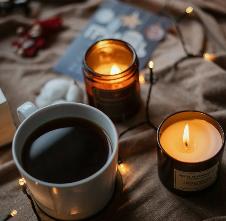 Taza de café caliente rodeada de velas y luces cálidas, evocando bienestar, calma y el ritual person