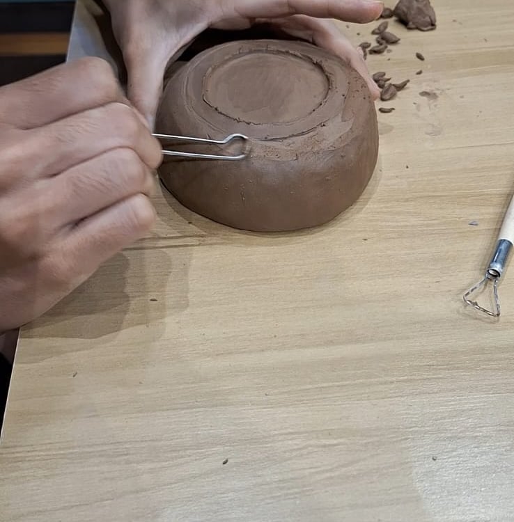 Indica pessoa fazendo acabamento na parte de baixo de uma peça