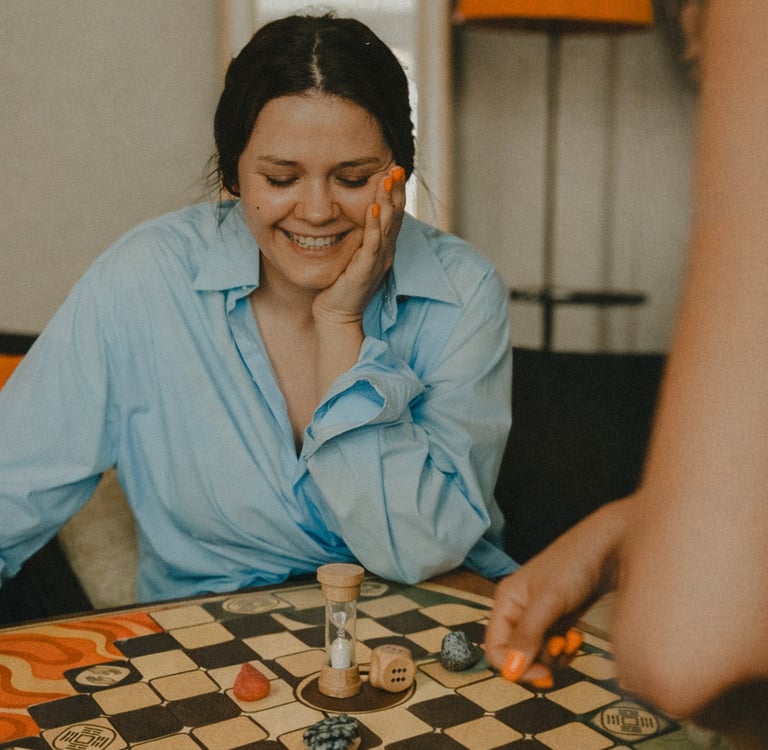 a woman sitting at a table with a game board game