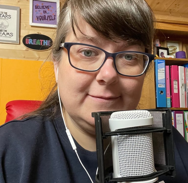 Laura Dumbleton at her recording setup with a microphone and BREATHE sign on the wall behind her
