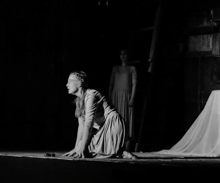 a woman in a long dress is kneeling on a stage