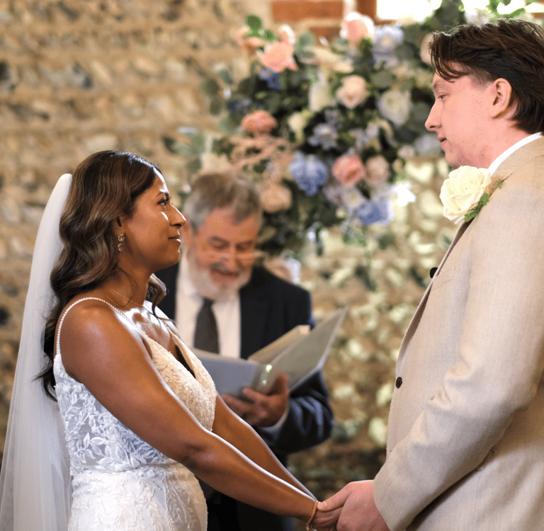 A bride and groom holding hands in a barn