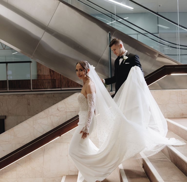 a bride and groom walking down a flight of stairs