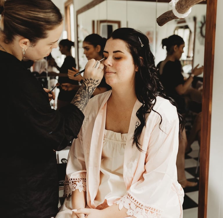 a woman getting her makeup done by a makeup artist