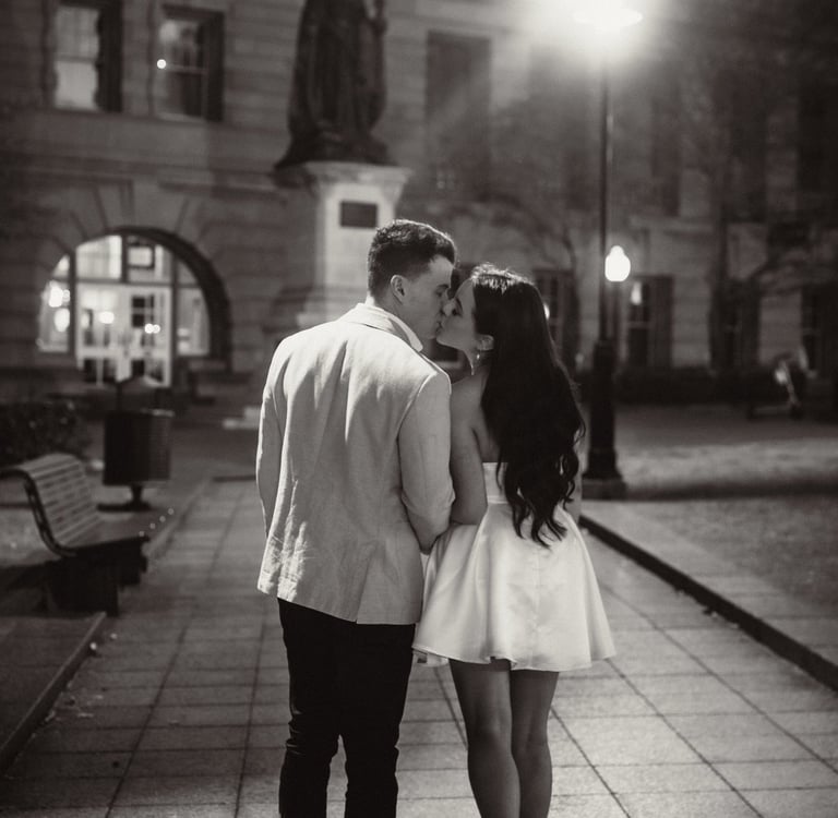 a couple kissing in a city street at night
