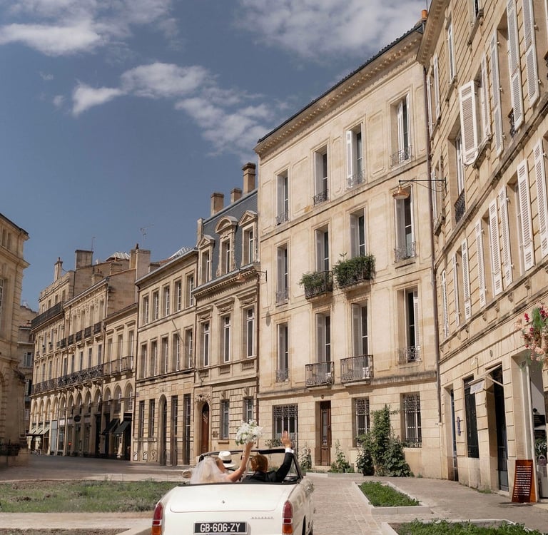 a white car driving down a cobblestone street wedding in Bordeaux