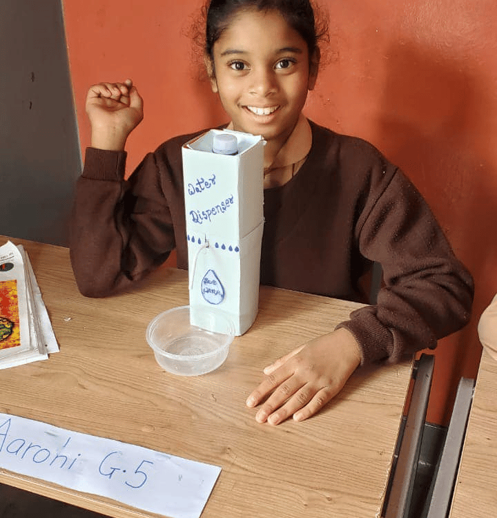 a young girl sitting at a table with a box of milk