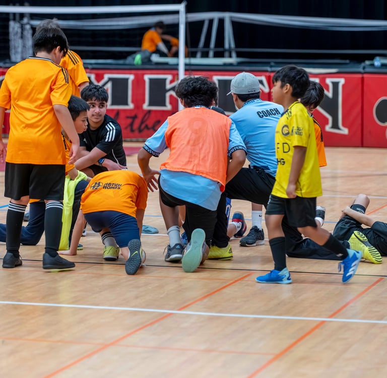 MVB F.C. huddle with their coach during recovery time after a youth soccer training session.