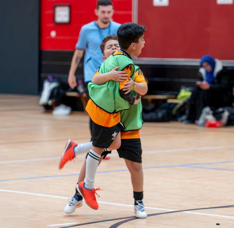 Two MVB FC players hugging and celebrating on an indoor soccer game in Mississauga