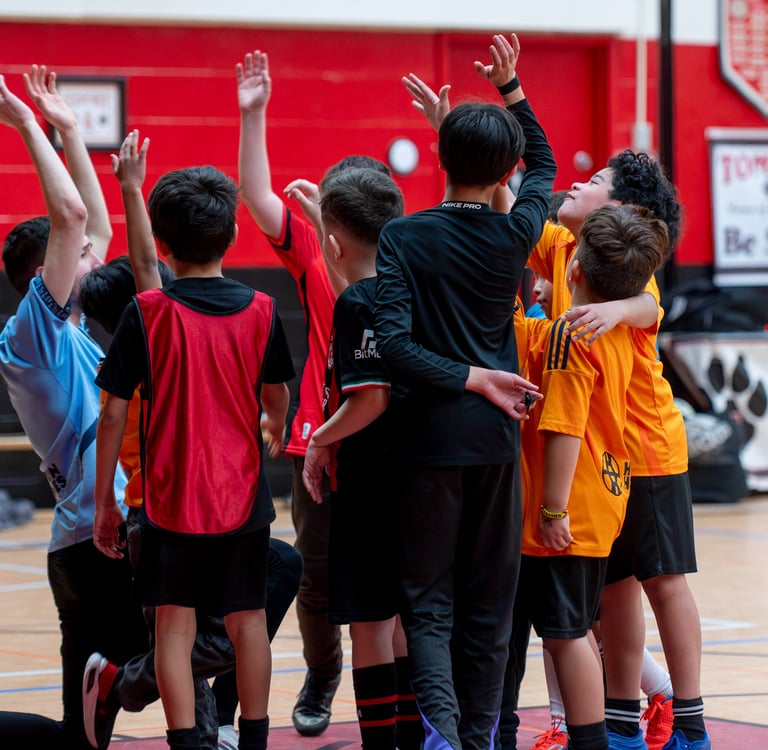 Young diverse MVB FC soccer players huddle together on an indoor soccer game in Mississauga