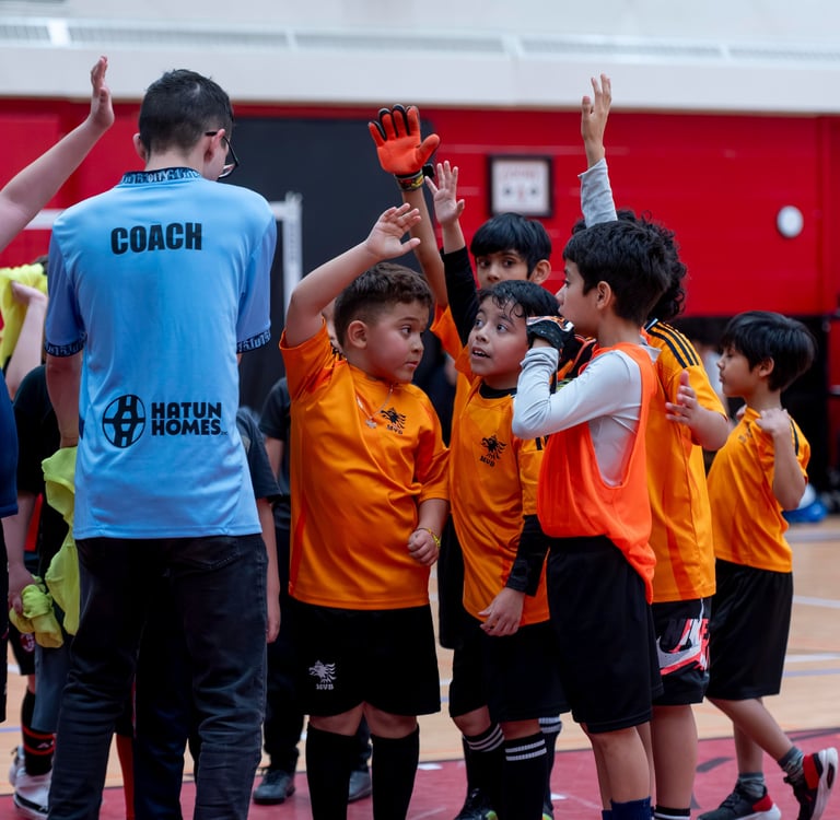 MVB FC soccer players  and their coach high-fiving during an indoor futsal game. Mississauga Soccer 