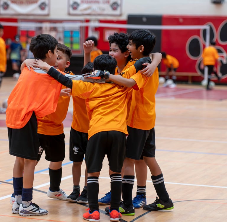 Young boys in MVB FC jerseys celebrating during an indoor soccer match in Soccer School Mississauga