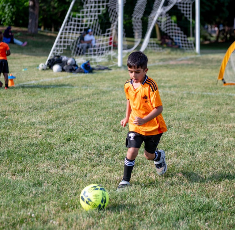 A young boy in an MVB F.C. jersey dribbles a soccer ball during a youth soccer practice  Mississaga