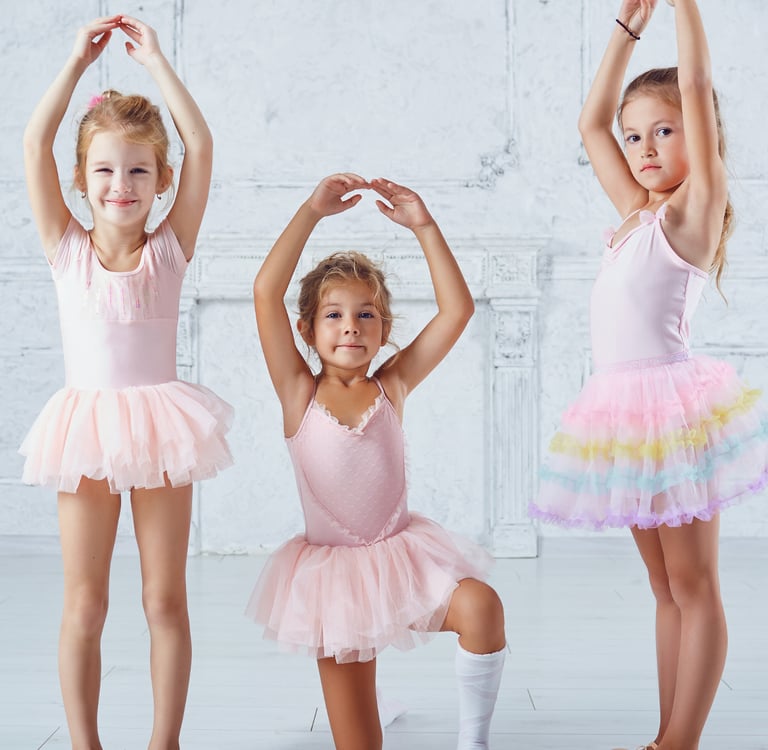 three little girls in ballet wear posing for a photo