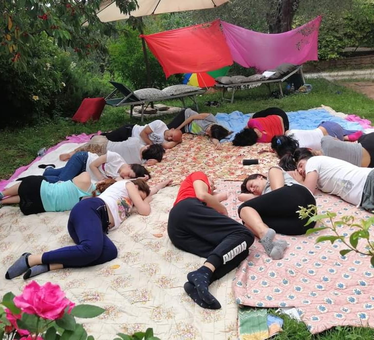 a group of people sitting on a blanket on a blanket, rilassamento, classe bioenergetica