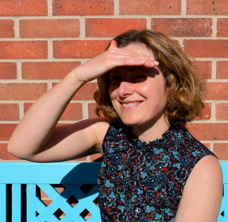 I am looking out past the camera to the garden, smiling, and shading my eyes from the sun