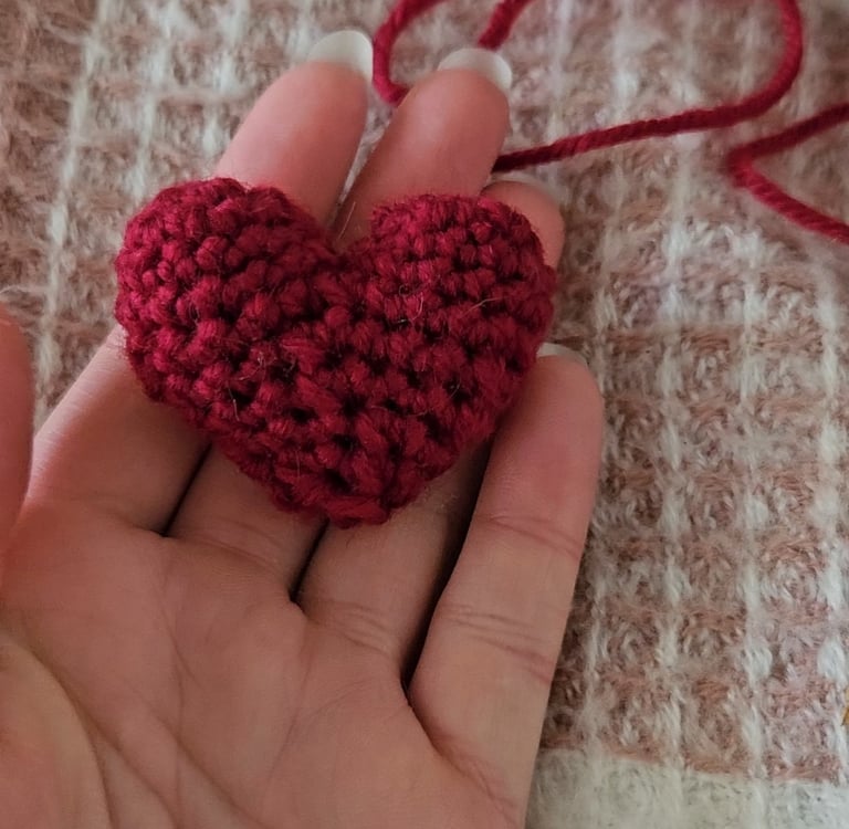 a red amigurumi heart in someones hand