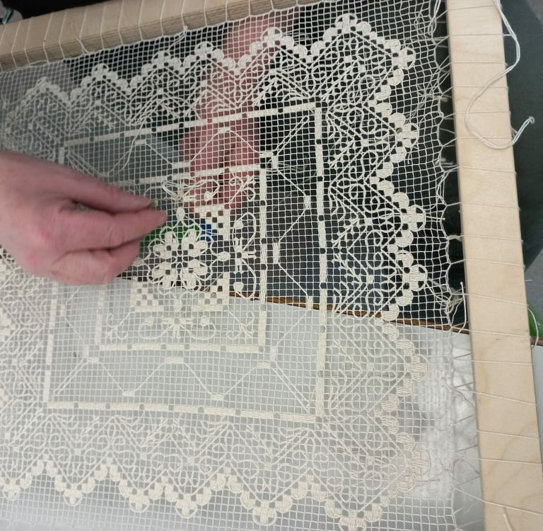 a person is holding a piece of lace and a needle