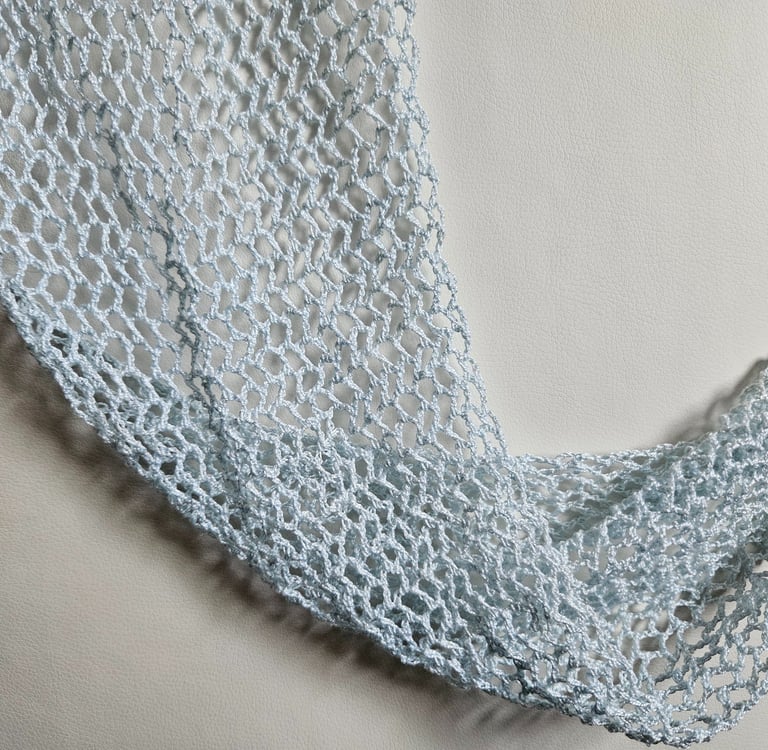 a crochet shawl draped on a white background
