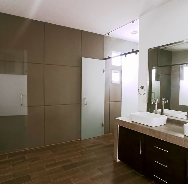 baño de recámara principal con espacios independientes y cancelería en cristal
