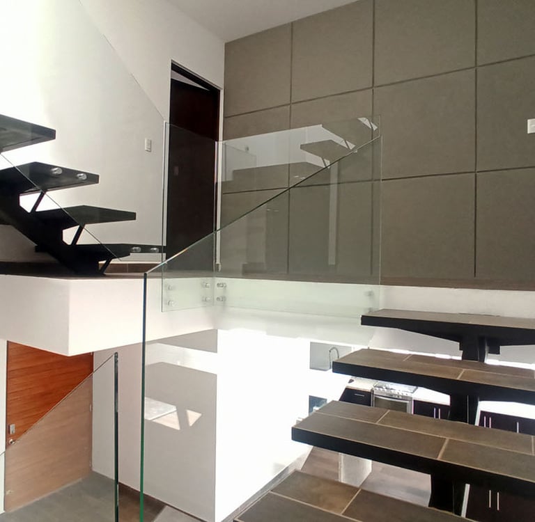 escalera panorámica que conecta los 3 niveles con barandal en cristal