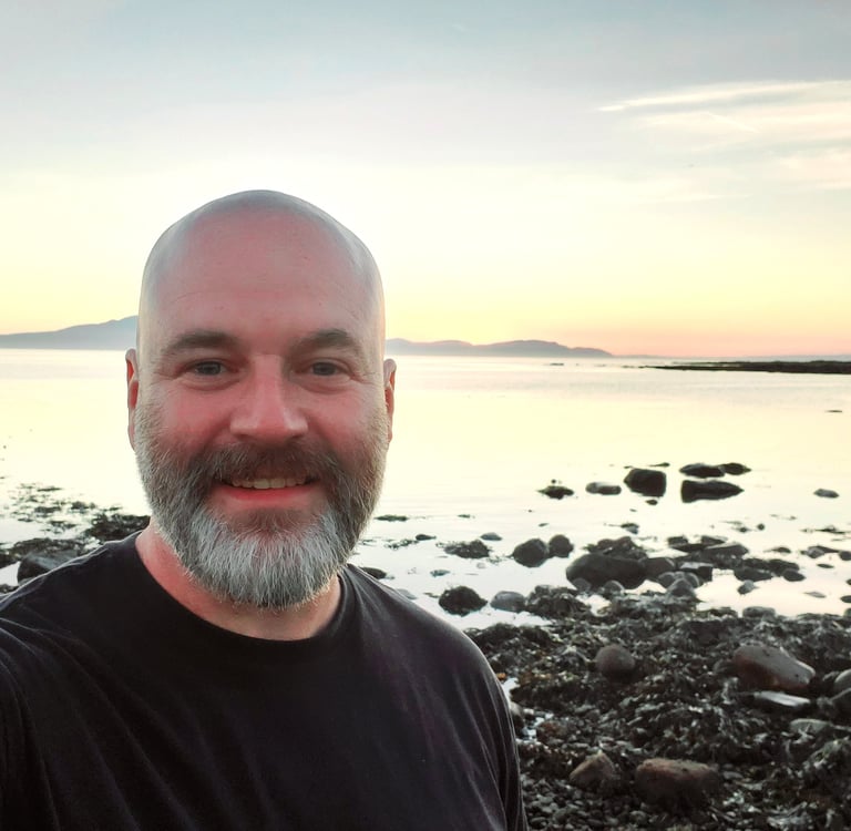 Photo of Life First Then Work founder Andy standing by the sea at sunset
