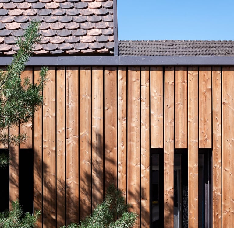 détail sur la jonction toiture traditionnelle et toiture plate avec continuité de bardage 
