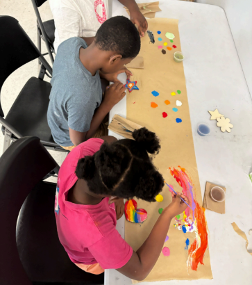Two kids at arts and crafts table making crafts