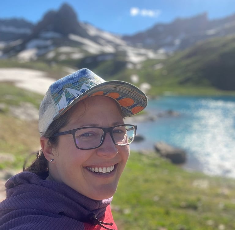 Jenna Smiling Outside in a hat by a lake