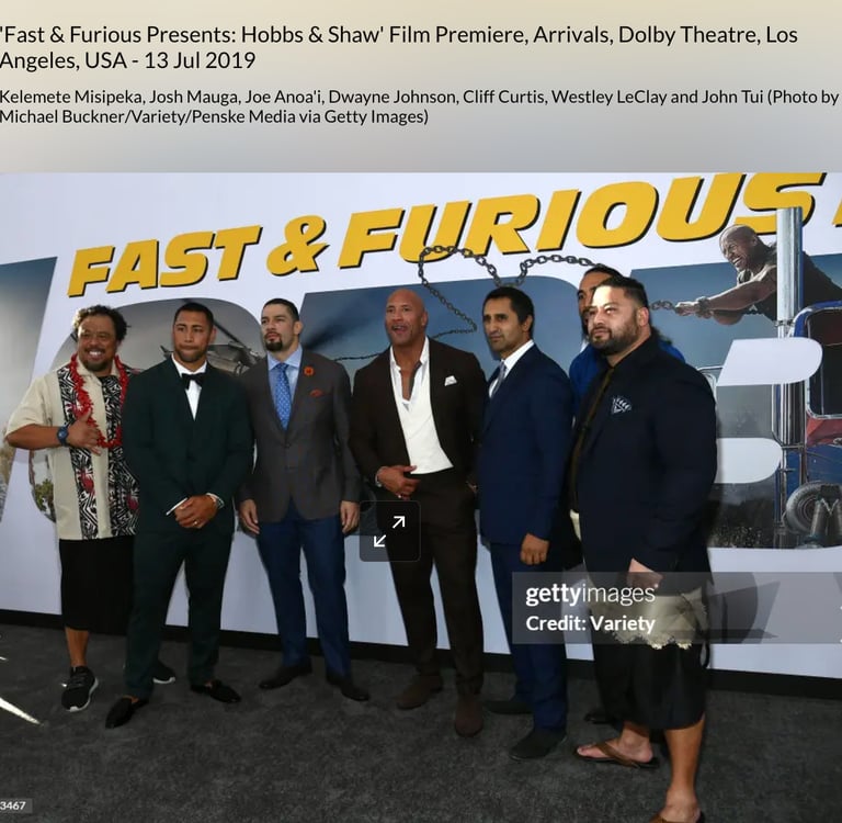 Dwayne Johnson with John Tui  in front of a fast & furious backdrop billboard 