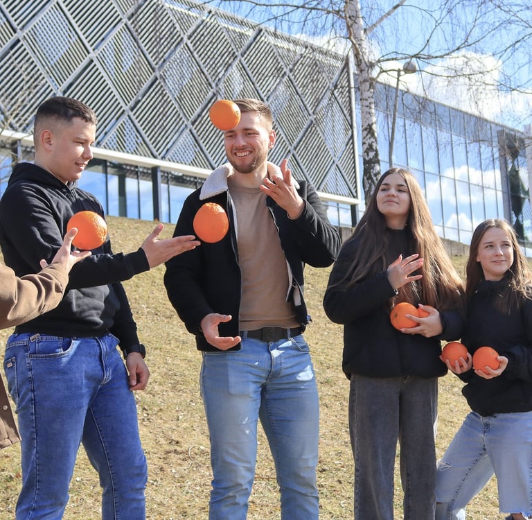 Jauni zmones lauke zaidzia su apelsinais