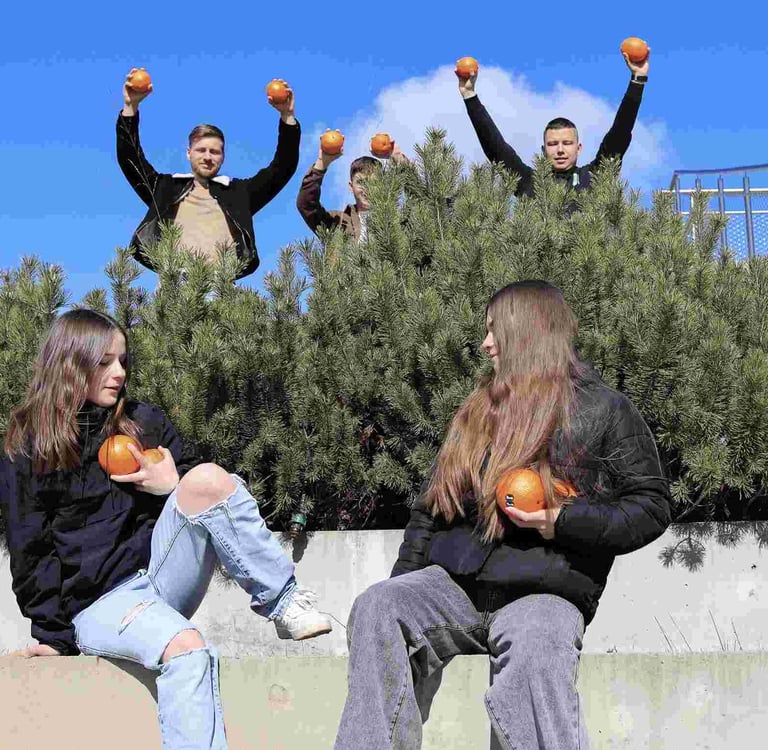 jauni zmones prie pusu stovi su apelsinais