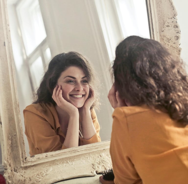 a woman in a yellow shirt is smiling and looking at her reflection in the mirror