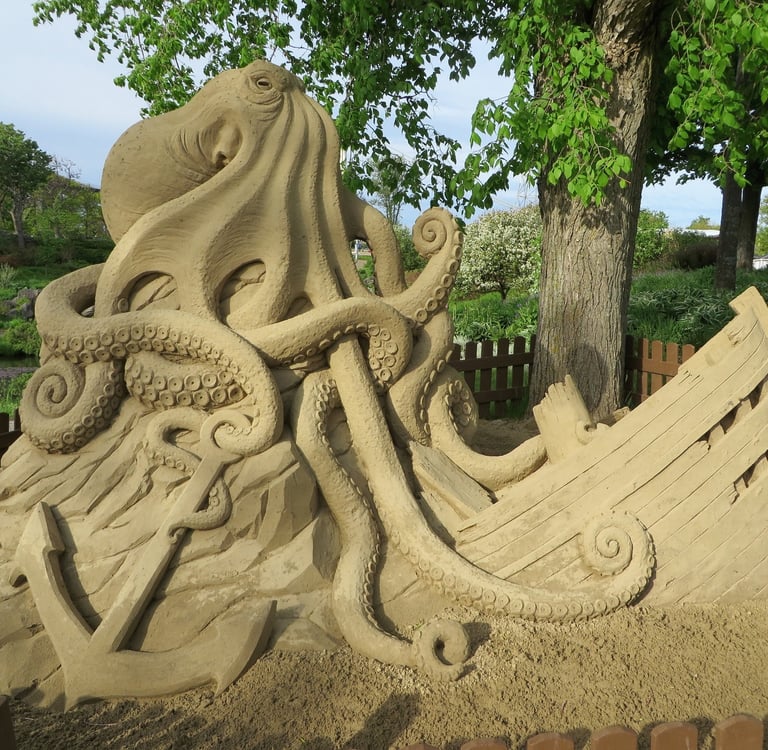 sand sculpture of a kraken with a sunken ship