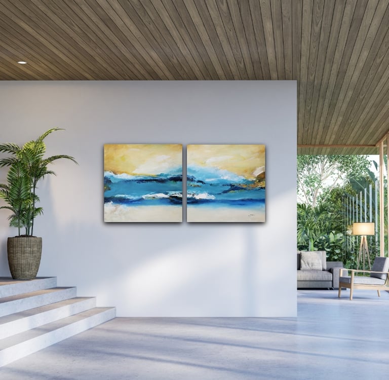 Two-piece abstract blue and gold ocean landscape art on a modern white living room wall.