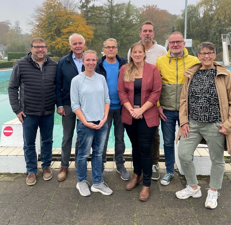 a group of people standing around a pool