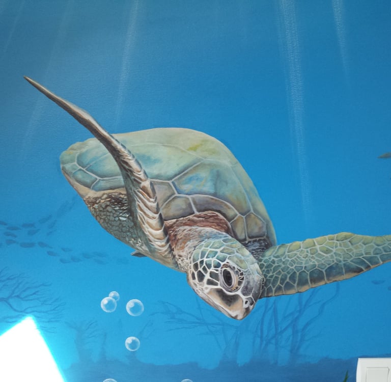 Fresque murale: une tortue de mer nageant, peinte sur un mur de chambre d'enfant.