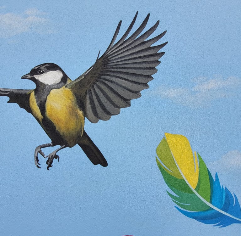 Fresque peinte sur une façade. Une mésange et une plume colorée s'envolent sur un ciel bleu.
