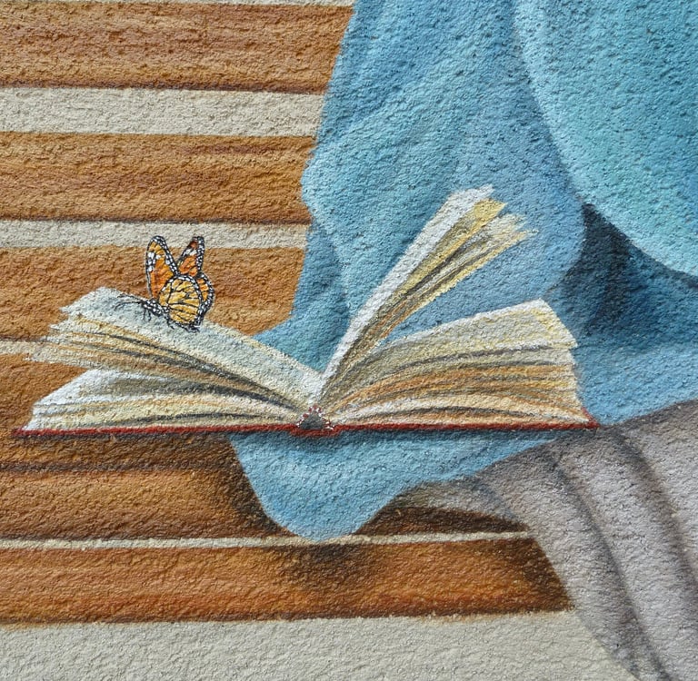 Fresque en trompe-l'oeil avec le détail d'un papillon posé sur un livre ouvert sur un banc.