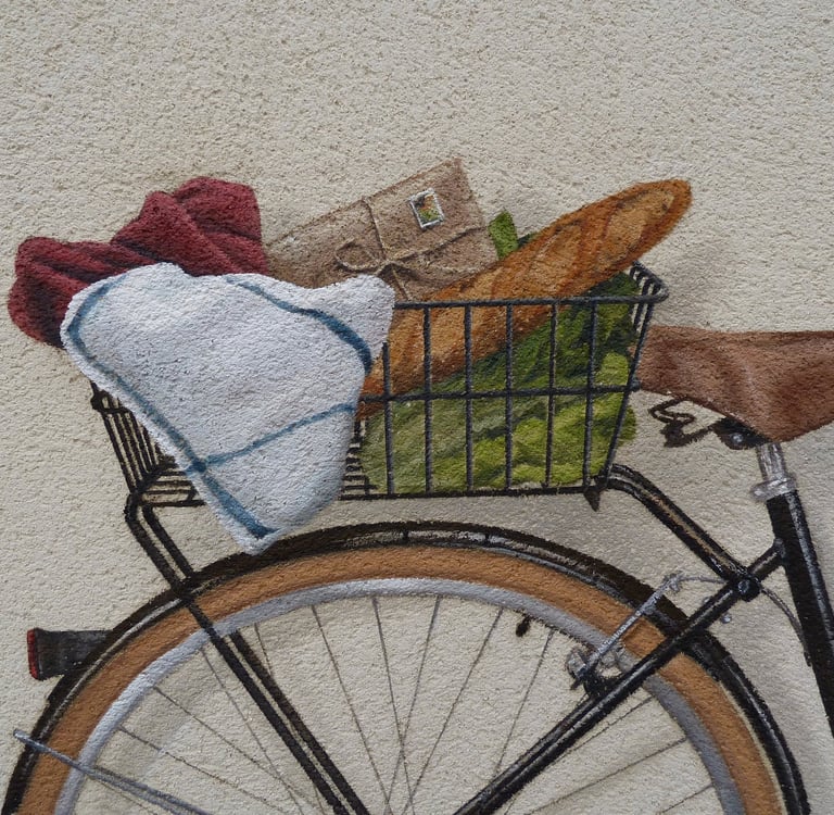 Détails d'un panier de vélo peint dans une fresque en trompe-l'oeil. Une baguette, une enveloppe.