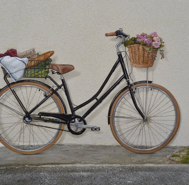 Un vélo peint en trompe-l'oeil sur une façade. Ses paniers emplient de fleurs et autres courses.
