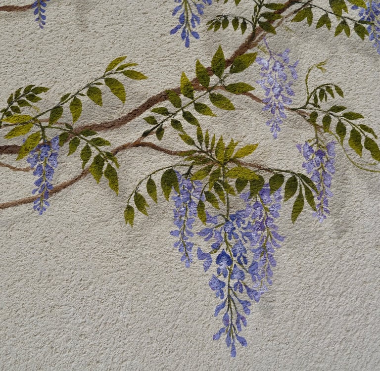 Détails d'une fresque peinte en trompe-l'oeil, une glycine décore une façade.